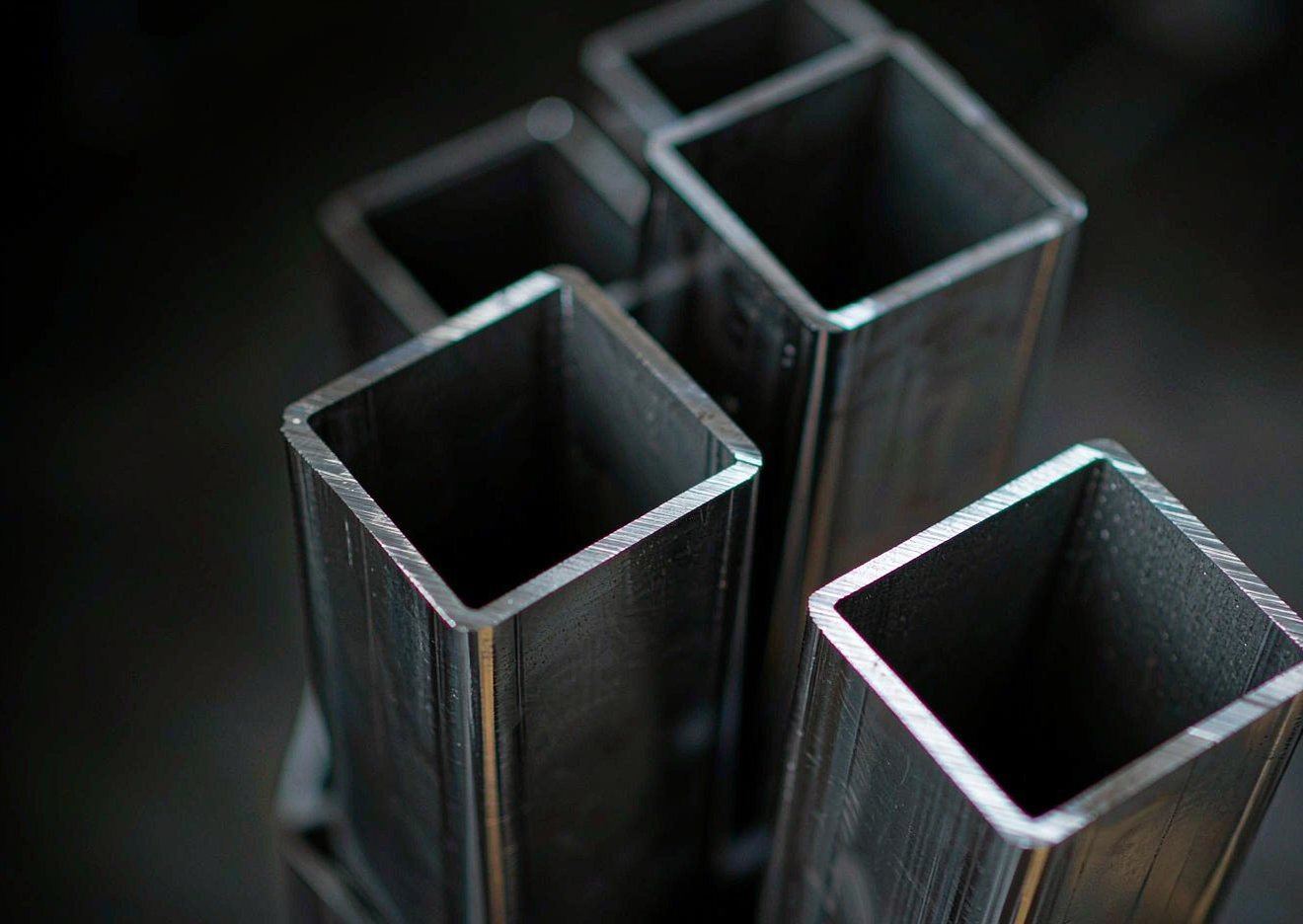 Clad square and rectangular tube ends showing the bright stainless face layer over the carbon steel wall