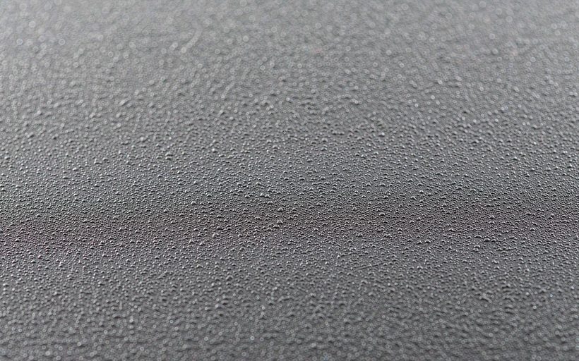 Bead-blasted matte stainless steel plate surface, macro detail of the stippled texture